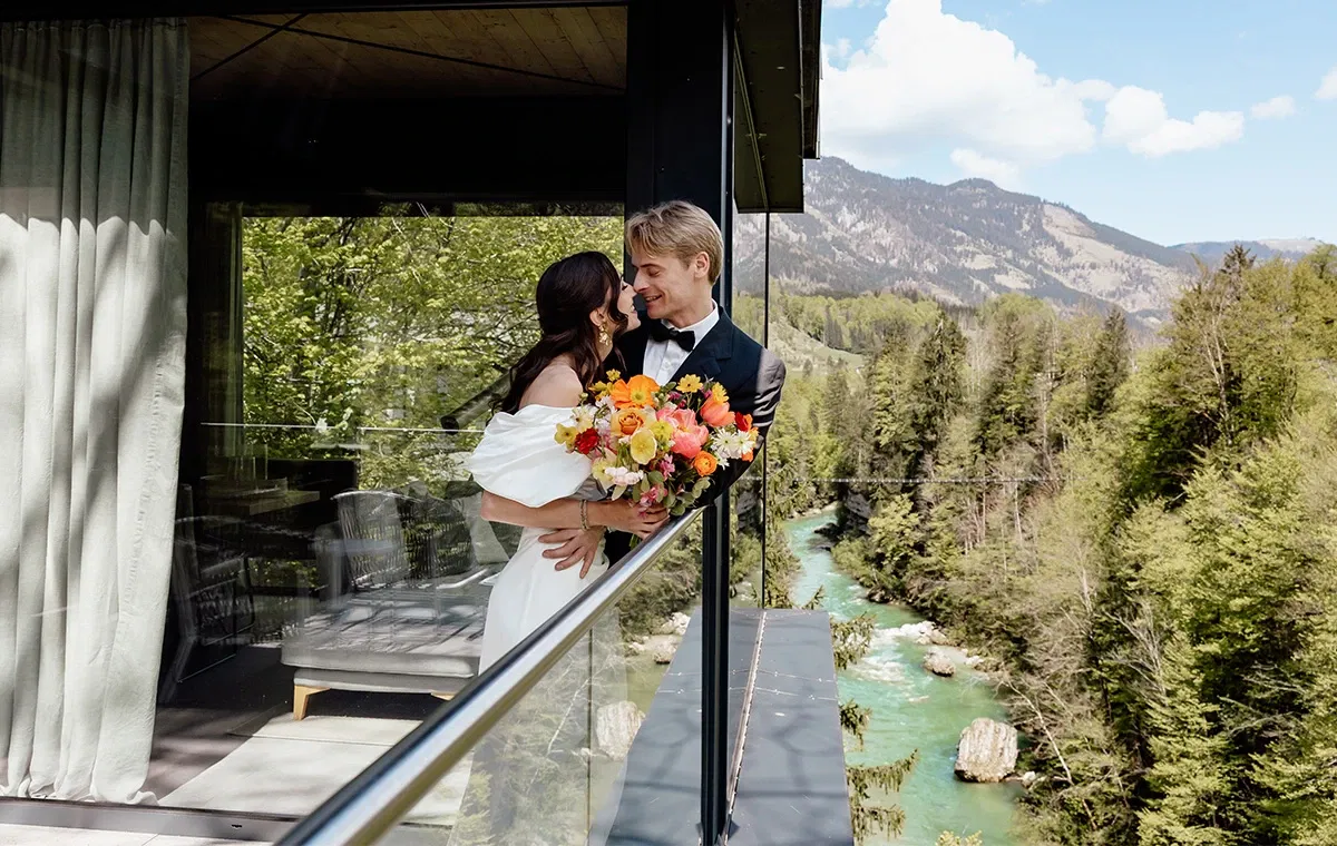 Brautpaar auf modernem Balkon mit Blick auf grüne Berge – Symbol einer eleganten Nature Wedding.