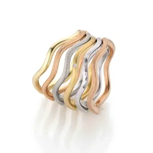 Wellenförmige Stapelringe in Gelbgold, Weißgold und Roségold, teils strukturiert und mit kleinem Diamantdetail in der Mitte.