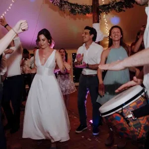 Braut und Gäste feiern ausgelassen auf der Tanzfläche, begleitet von Trommelrhythmen.