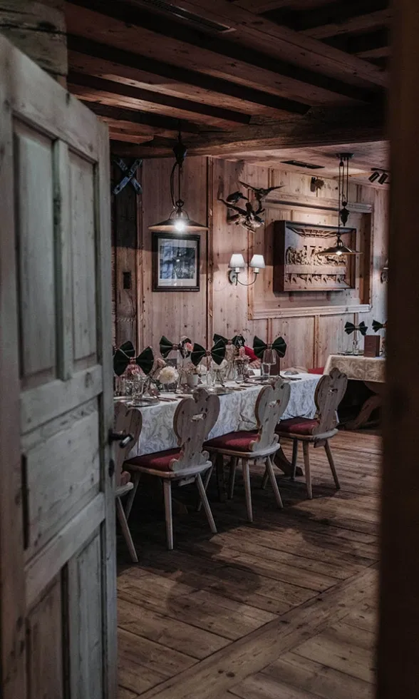 Rustikaler Hochzeitsraum in einer Berghütte mit gedeckter Tafel, Holzstühlen und liebevoll arrangierter Tischdekoration in warmem Licht.