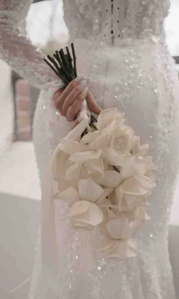 Minimalistischer Brautstrauß aus zarten weißen Blüten, gehalten von einer Braut im schlichten, modernen Kleid.