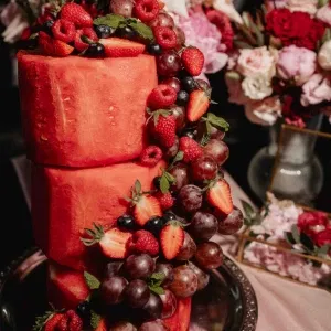 Mehrstöckige Hochzeitstorte aus frischer Wassermelone, dekoriert mit Erdbeeren, Himbeeren, Trauben und Beeren – kreative, sommerliche Alternative zur klassischen Hochzeitstorte.