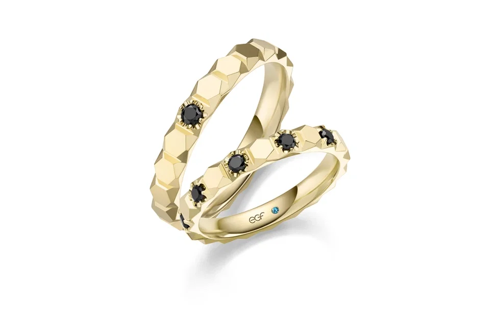 Modernes Trauringpaar aus Gelbgold mit facettierter Oberfläche und schwarzen Diamanten aus der EGF Manufaktur.
