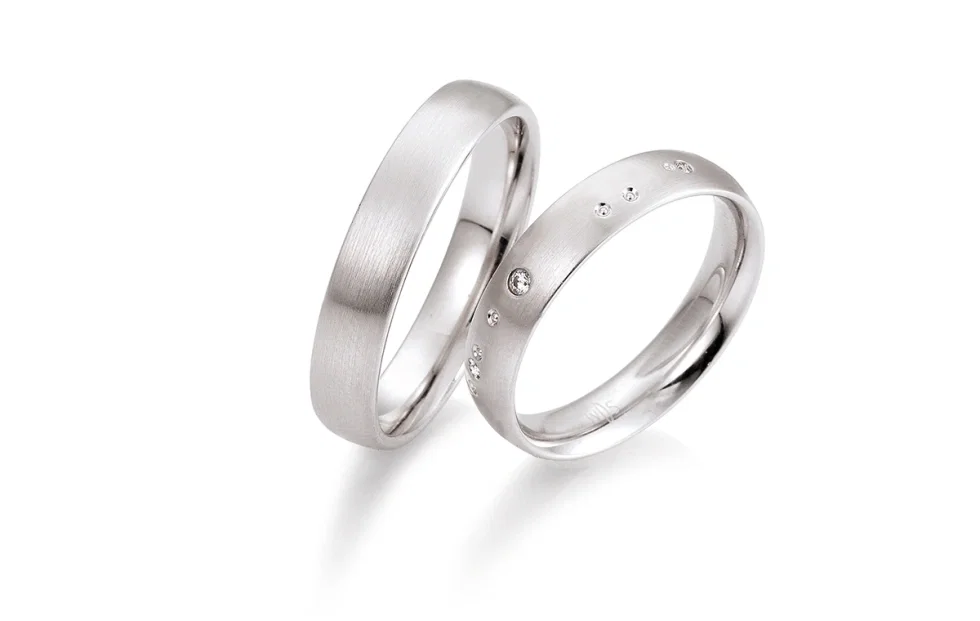 Zeitloses Trauringpaar aus Weißgold mit dezent gefassten Diamanten von Saint Maurice.