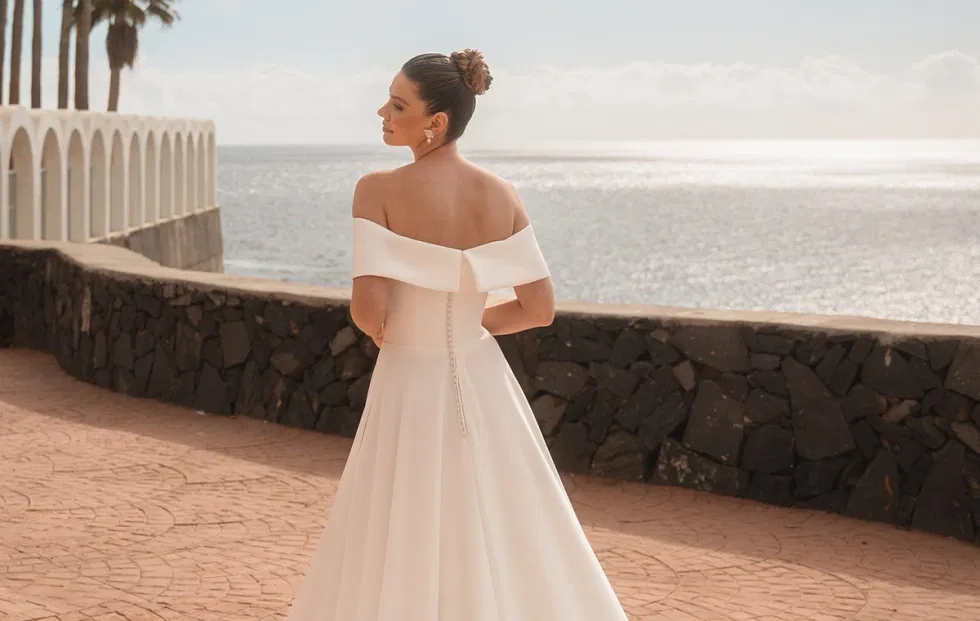 Off-Shoulder-Brautkleid von Diane Legrand mit fließendem Rock und eleganter Rückansicht am Meer.