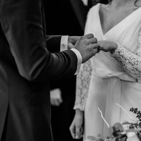 Schwarz-weiß-Aufnahme vom Ringtausch während einer freien Trauung – Braut und Bräutigam stecken sich während der Hochzeitszeremonie die Ringe an.