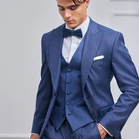 Detailaufnahme eines Bräutigams im dunkelblauen Hochzeitsanzug mit strukturierter Weste und Fliege.