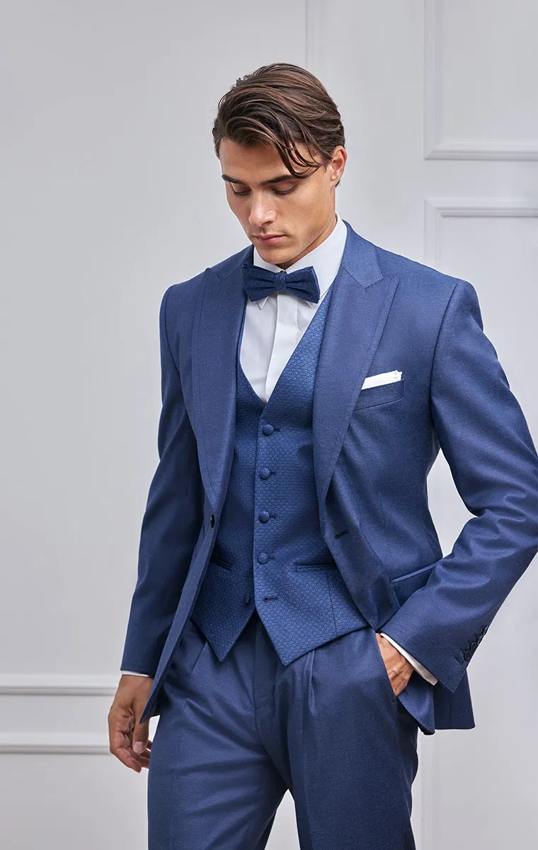 Detailaufnahme eines Bräutigams im dunkelblauen Hochzeitsanzug mit strukturierter Weste und Fliege.