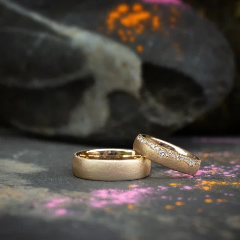 Individuelle Trauringe aus Gold mit Diamantbesatz auf dunklem Hintergrund – handgefertigt in der Trauringmanufaktur Birte Schumacher