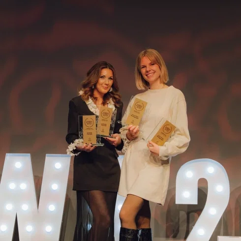 Zwei Gewinnerinnen des Austrian Wedding Award 2026 stehen auf der Bühne und präsentieren stolz ihre Auszeichnungen vor beleuchtetem Hintergrund