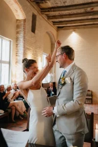 Braut jubelt voller Freude während der Zeremonie und feiert gemeinsam mit ihrem Partner den emotionalen Ja-Moment.