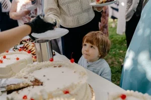 Kleiner Hochzeitsgast schaut begeistert auf die Hochzeitstorten und wartet gespannt auf ein Stück Kuchen.