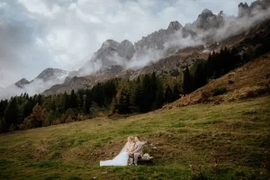 Frisch verheiratetes Paar sitzt gemeinsam auf einer Bank vor imposanter Bergkulisse und genießt die Ruhe der Natur.