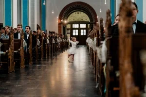 Kleines Mädchen tanzt ausgelassen allein durch den Mittelgang der Kirche und begeistert die Hochzeitsgäste.