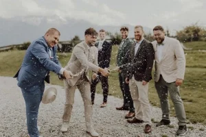 Männergruppe öffnet lachend Champagnerflaschen im Freien, während der Schaum durch die Luft spritzt.
