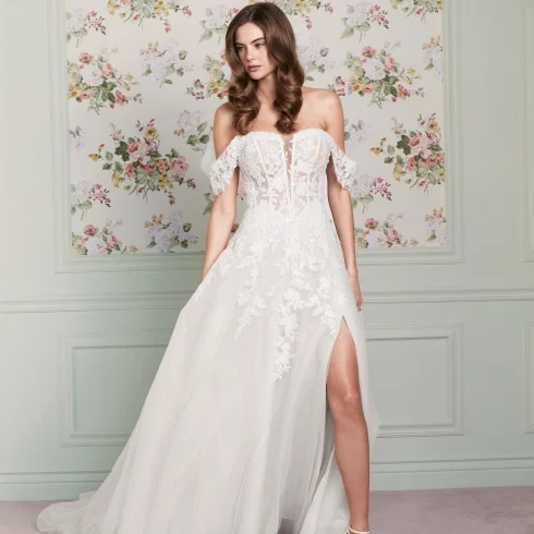 Dieses A-Linien-Brautkleid „Maisie" von Adore by Justin Alexander besticht mit floraler Spitze, Off-Shoulder-Ärmeln und einem hohen Beinschlitz für einen romantischen, verführerischen Look.
