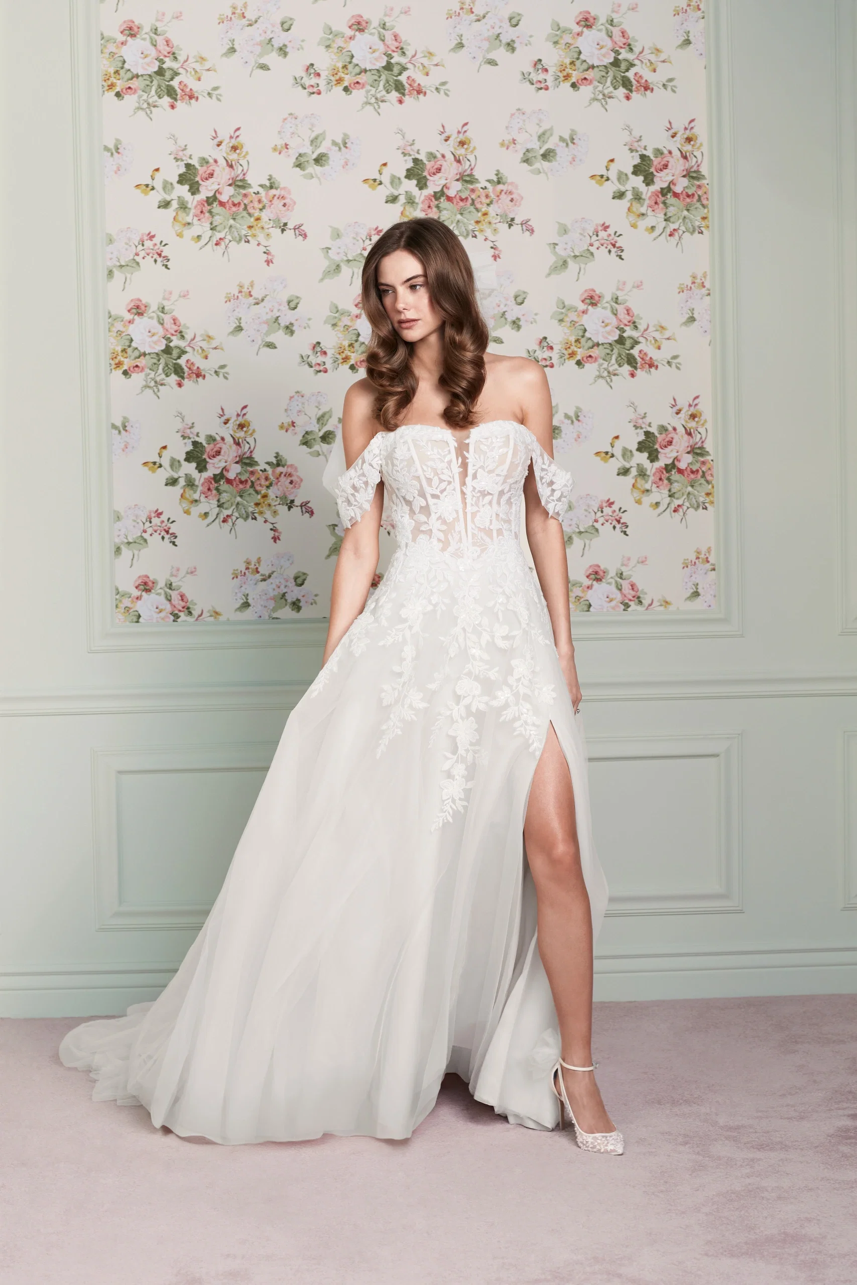Dieses A-Linien-Brautkleid „Maisie" von Adore by Justin Alexander besticht mit floraler Spitze, Off-Shoulder-Ärmeln und einem hohen Beinschlitz für einen romantischen, verführerischen Look.